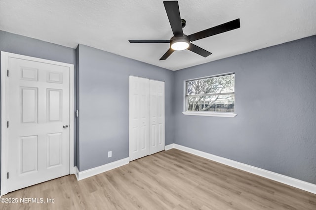 unfurnished bedroom featuring ceiling fan, a closet, wood finished floors, and baseboards