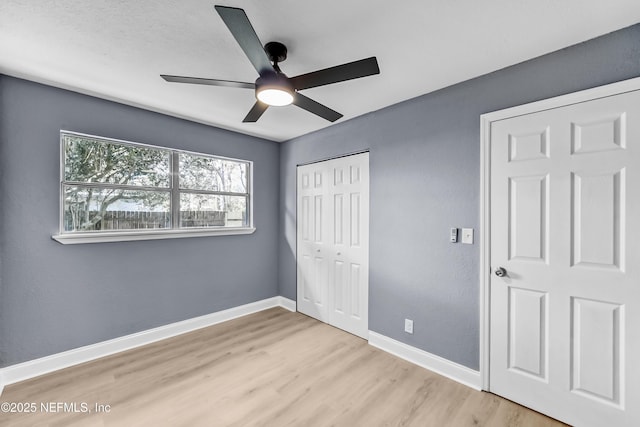 unfurnished bedroom with ceiling fan, a closet, baseboards, and wood finished floors