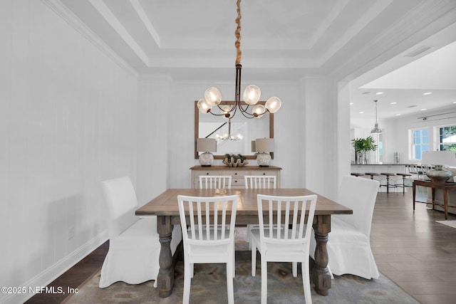 dining area featuring visible vents, a raised ceiling, a notable chandelier, and wood finished floors