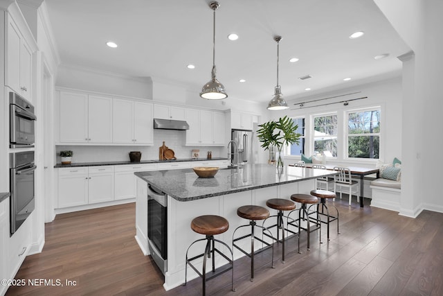 kitchen featuring under cabinet range hood, white cabinetry, tasteful backsplash, and dark wood-type flooring