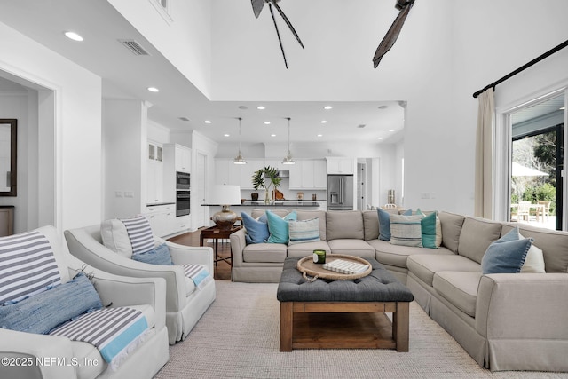 living room featuring a high ceiling, recessed lighting, and visible vents