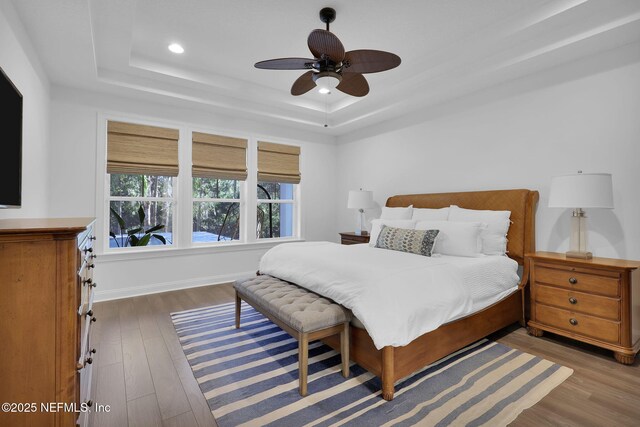 bedroom featuring ceiling fan, baseboards, recessed lighting, wood finished floors, and a raised ceiling