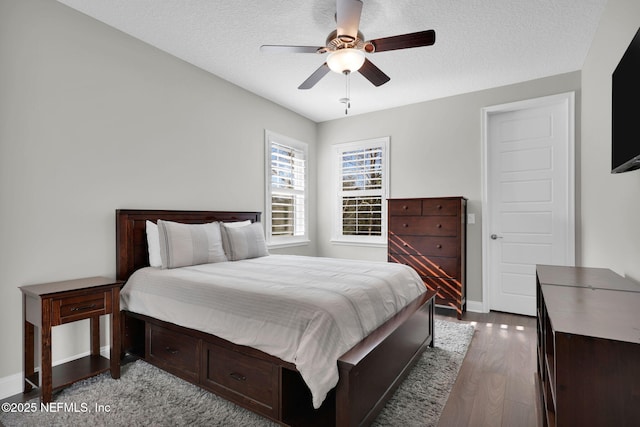 bedroom featuring baseboards, a textured ceiling, wood finished floors, and a ceiling fan