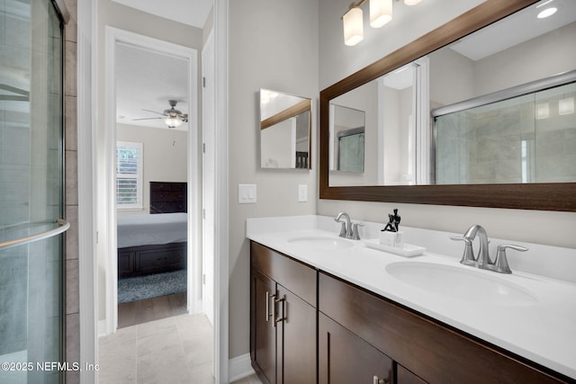 ensuite bathroom featuring a tile shower, connected bathroom, a ceiling fan, and a sink