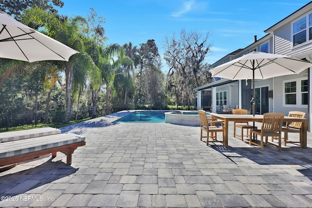 view of pool featuring outdoor dining area, fence, a pool with connected hot tub, and a patio area