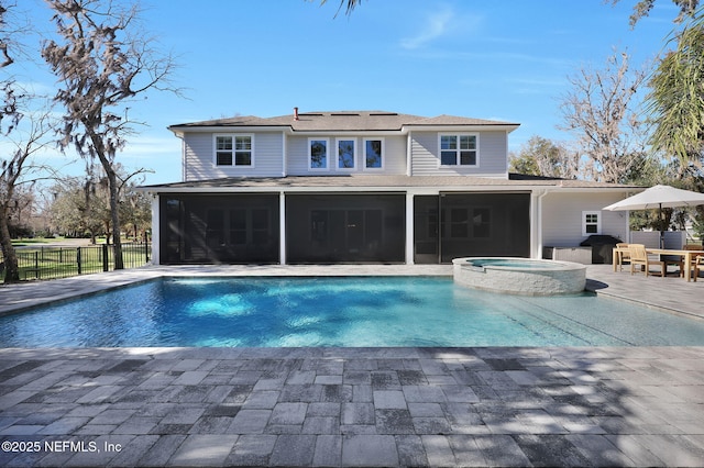 view of swimming pool with a pool with connected hot tub, fence, a sunroom, and a patio