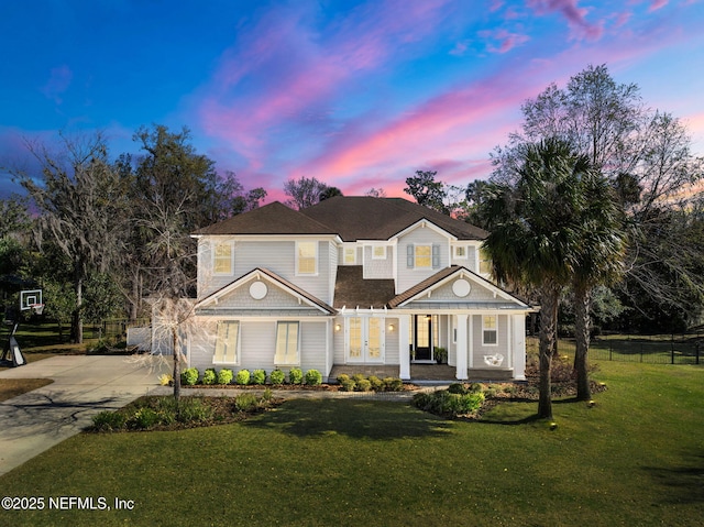 view of front of home featuring fence, a porch, a yard, concrete driveway, and french doors