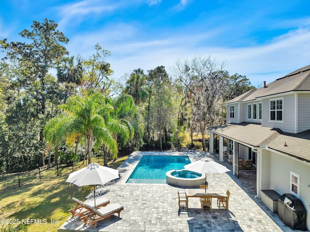 view of swimming pool featuring a patio area, a lawn, a pool with connected hot tub, and fence