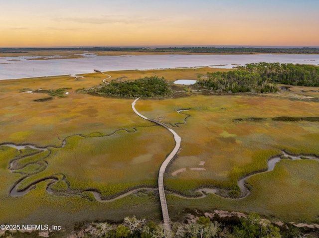 aerial view at dusk featuring a water view