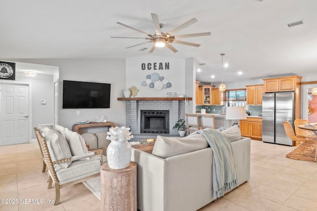 living room with lofted ceiling, light tile patterned flooring, a fireplace, and visible vents