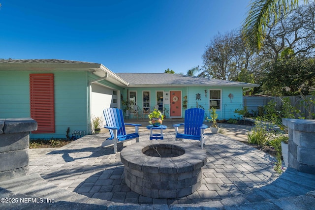 view of patio with an outdoor fire pit, fence, and an attached garage