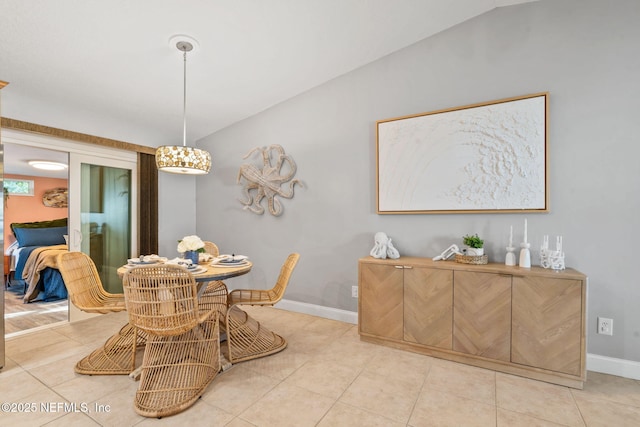 tiled dining area featuring lofted ceiling and baseboards