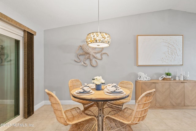 dining room featuring light tile patterned floors, baseboards, and vaulted ceiling