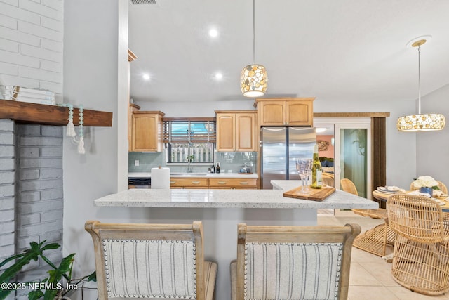 kitchen with light tile patterned floors, a breakfast bar area, backsplash, freestanding refrigerator, and pendant lighting