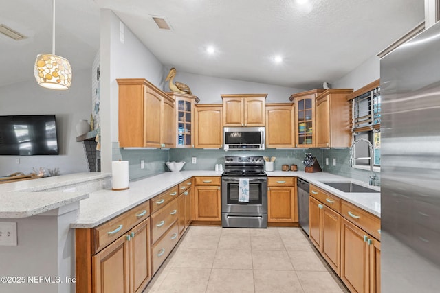 kitchen with light tile patterned floors, a peninsula, a sink, vaulted ceiling, and appliances with stainless steel finishes