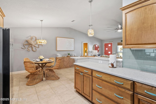 kitchen featuring ceiling fan, lofted ceiling, freestanding refrigerator, tasteful backsplash, and pendant lighting