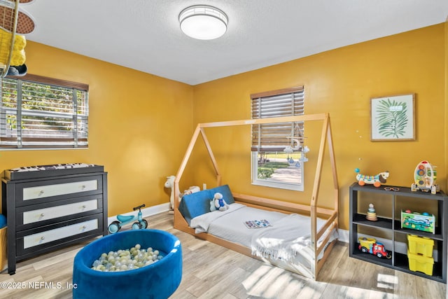 workout area with a textured ceiling, baseboards, and wood finished floors