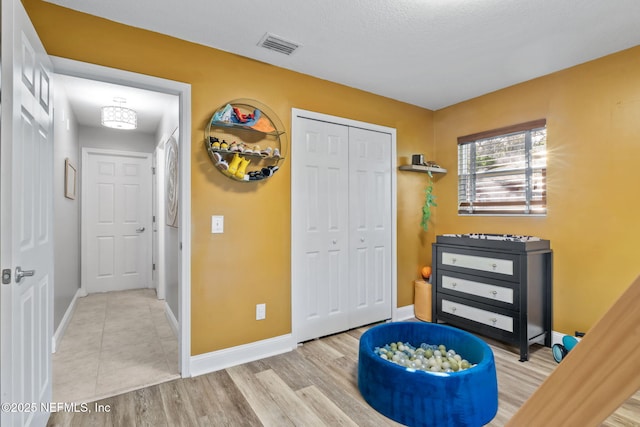 bedroom featuring a closet, wood finished floors, visible vents, and baseboards