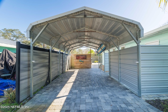 view of vehicle parking with fence and a detached carport