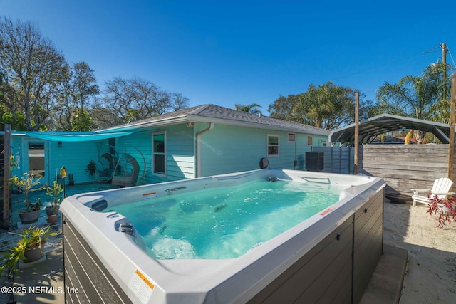 back of property with a hot tub, fence, central AC, and a detached carport