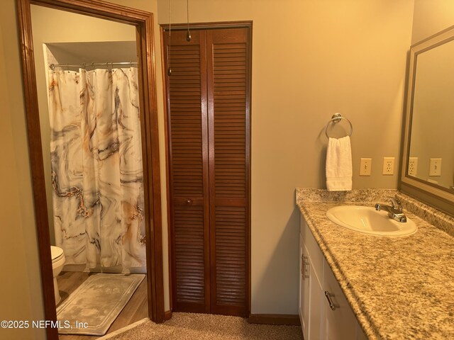 bathroom with a closet, a shower with shower curtain, vanity, and toilet