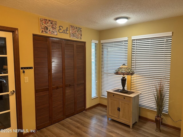 bedroom featuring a textured ceiling, a closet, baseboards, and wood finished floors