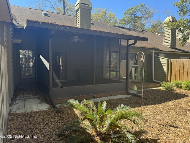 rear view of property featuring a shingled roof, a chimney, fence, and a sunroom