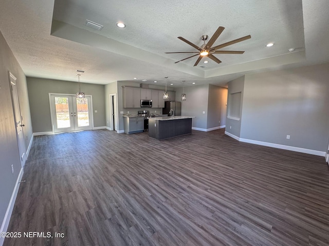 unfurnished living room with visible vents, baseboards, a raised ceiling, dark wood-type flooring, and a textured ceiling