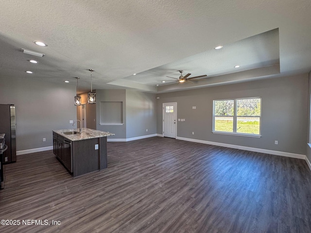 kitchen with dark wood-type flooring, a sink, baseboards, freestanding refrigerator, and a raised ceiling