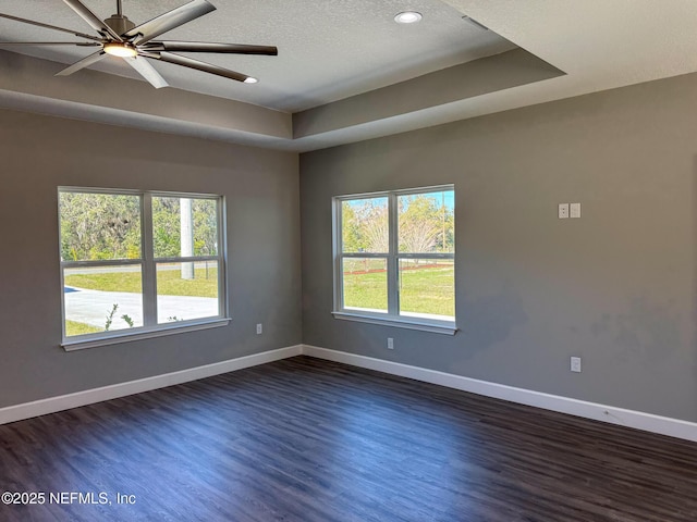 spare room featuring a healthy amount of sunlight, baseboards, and dark wood-style flooring