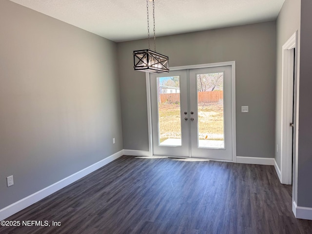 unfurnished dining area with dark wood-style floors, baseboards, and a textured ceiling