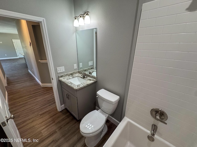 bathroom with baseboards, toilet, wood finished floors, vanity, and washtub / shower combination