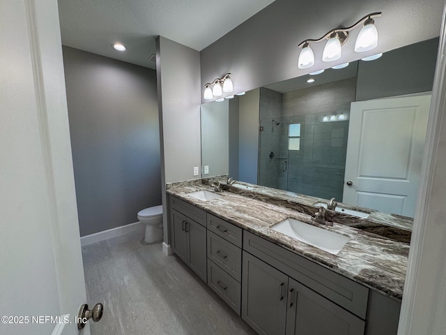 full bath with a sink, a shower stall, baseboards, and double vanity