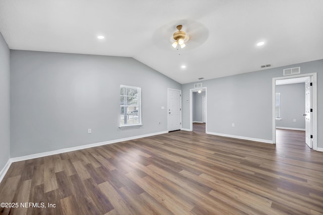 empty room featuring baseboards, visible vents, vaulted ceiling, and dark wood-type flooring