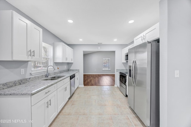 kitchen featuring stainless steel appliances, recessed lighting, a high end fireplace, white cabinetry, and a sink