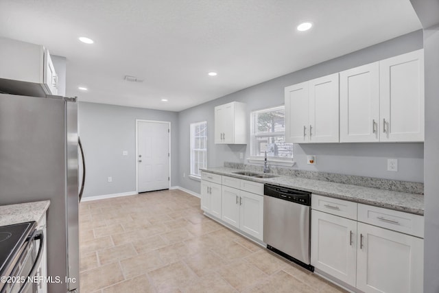 kitchen with white cabinets, light stone counters, appliances with stainless steel finishes, a sink, and recessed lighting