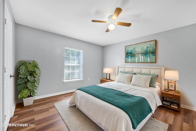 bedroom featuring ceiling fan, a textured ceiling, wood finished floors, and baseboards