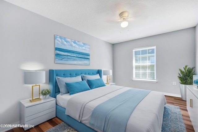 bedroom featuring a textured ceiling, baseboards, and wood finished floors