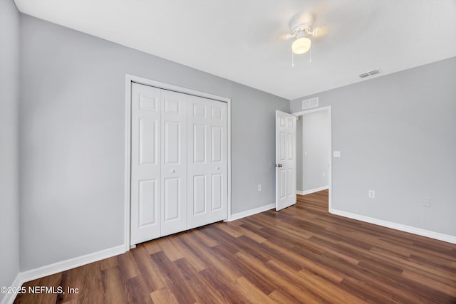 unfurnished bedroom with a closet, wood finished floors, visible vents, and baseboards