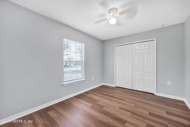 unfurnished bedroom featuring baseboards, a ceiling fan, wood finished floors, a textured ceiling, and a closet