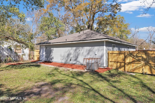 rear view of house with cooling unit, fence, and a lawn