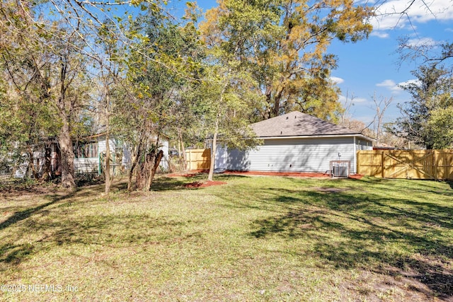 view of yard featuring fence and central AC