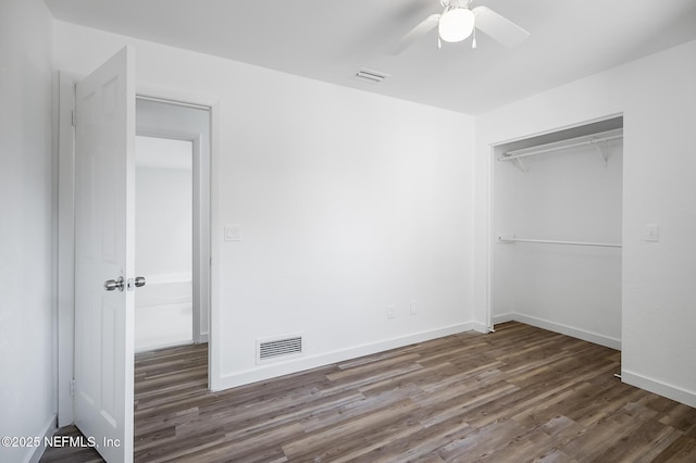 unfurnished bedroom featuring wood finished floors, visible vents, a closet, and baseboards