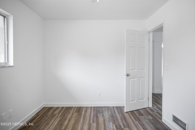 unfurnished room with wood finished floors, visible vents, and baseboards