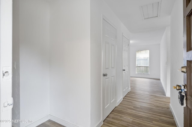 hallway featuring wood finished floors and baseboards