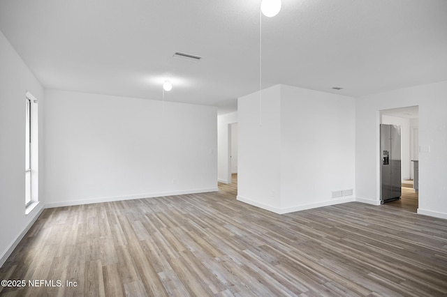 empty room featuring visible vents, baseboards, and wood finished floors