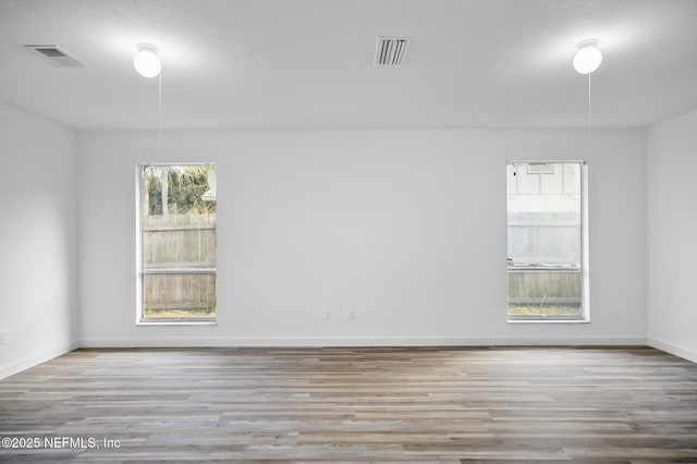 spare room featuring visible vents, baseboards, and wood finished floors