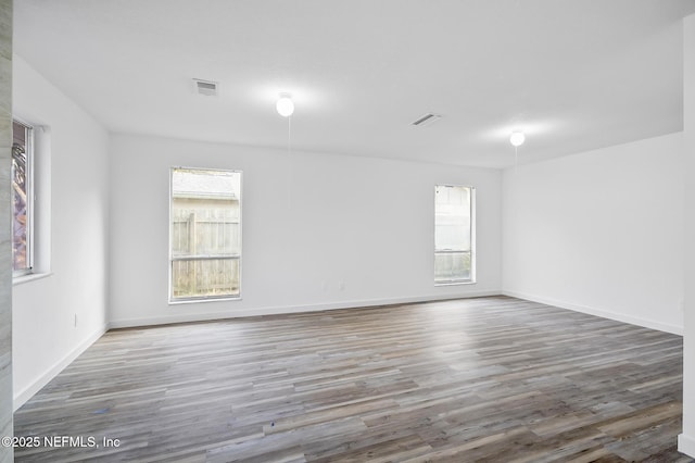 spare room featuring visible vents, baseboards, and wood finished floors