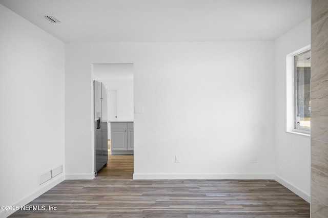 spare room with visible vents, baseboards, and wood finished floors