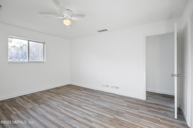 unfurnished room featuring ceiling fan, visible vents, baseboards, and wood finished floors